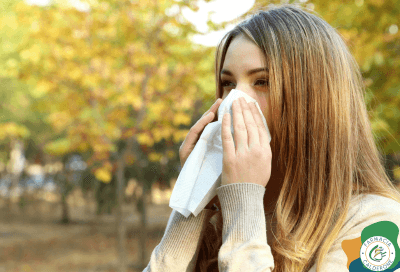 Donna all’aperto che si soffia il naso con un fazzoletto a causa delle allergie di fine estate.
