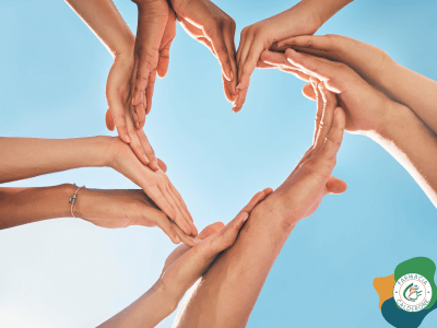 Mani di più persone che formano un cuore contro il cielo azzurro, simbolo di prevenzione e unione per la salute del cuore.