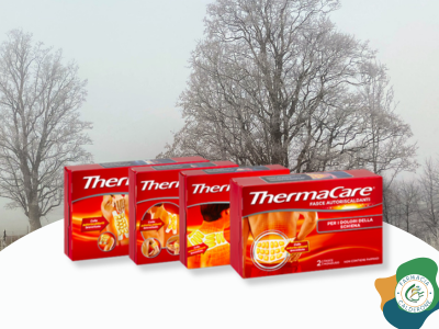 Confezioni di cerotti autoriscaldanti ThermaCare davanti a uno sfondo invernale con alberi, simbolo di sollievo dal dolore e comfort durante il freddo.